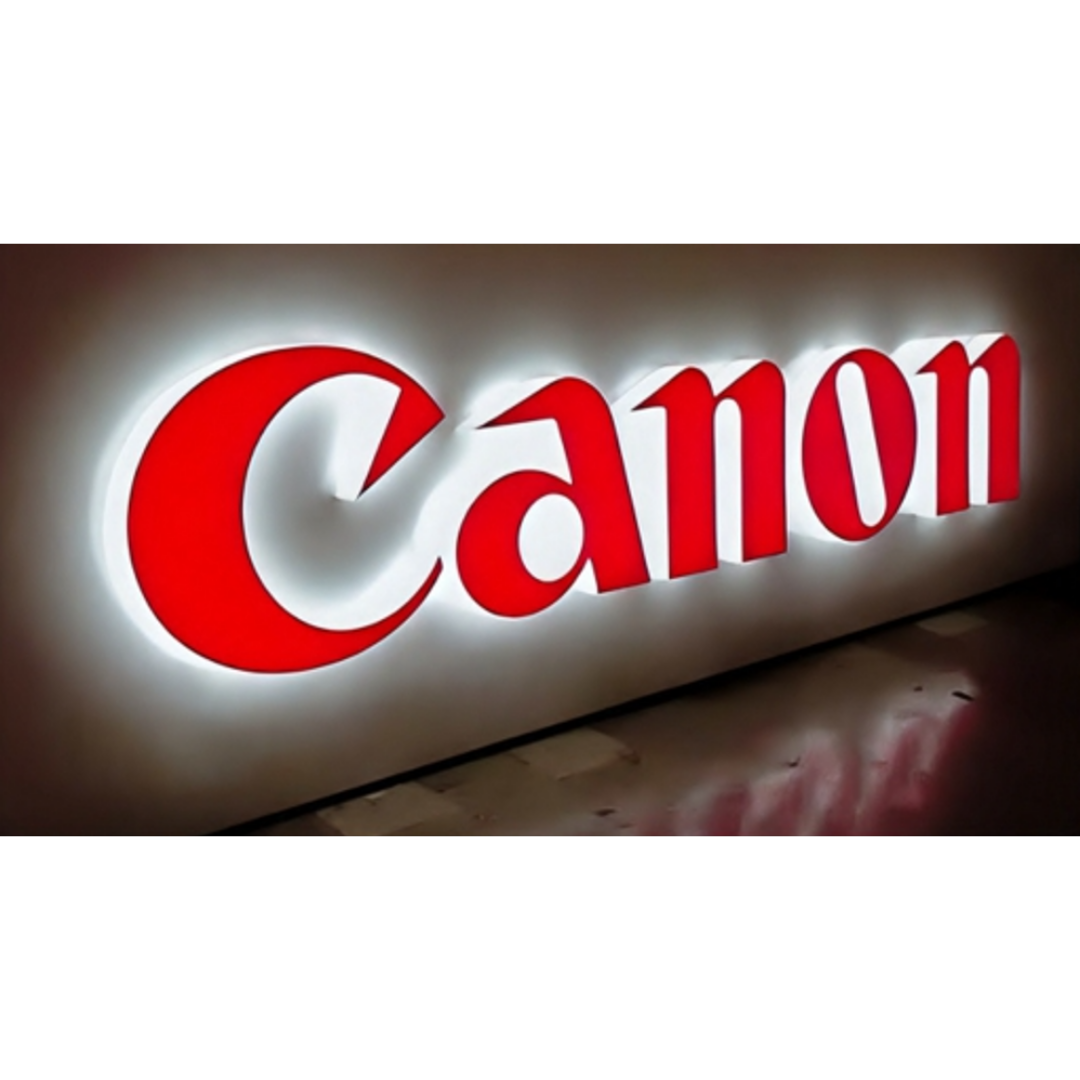 Large red raised letters spelling “Canon” on a light-colored panel, surrounded by bright white backlighting.