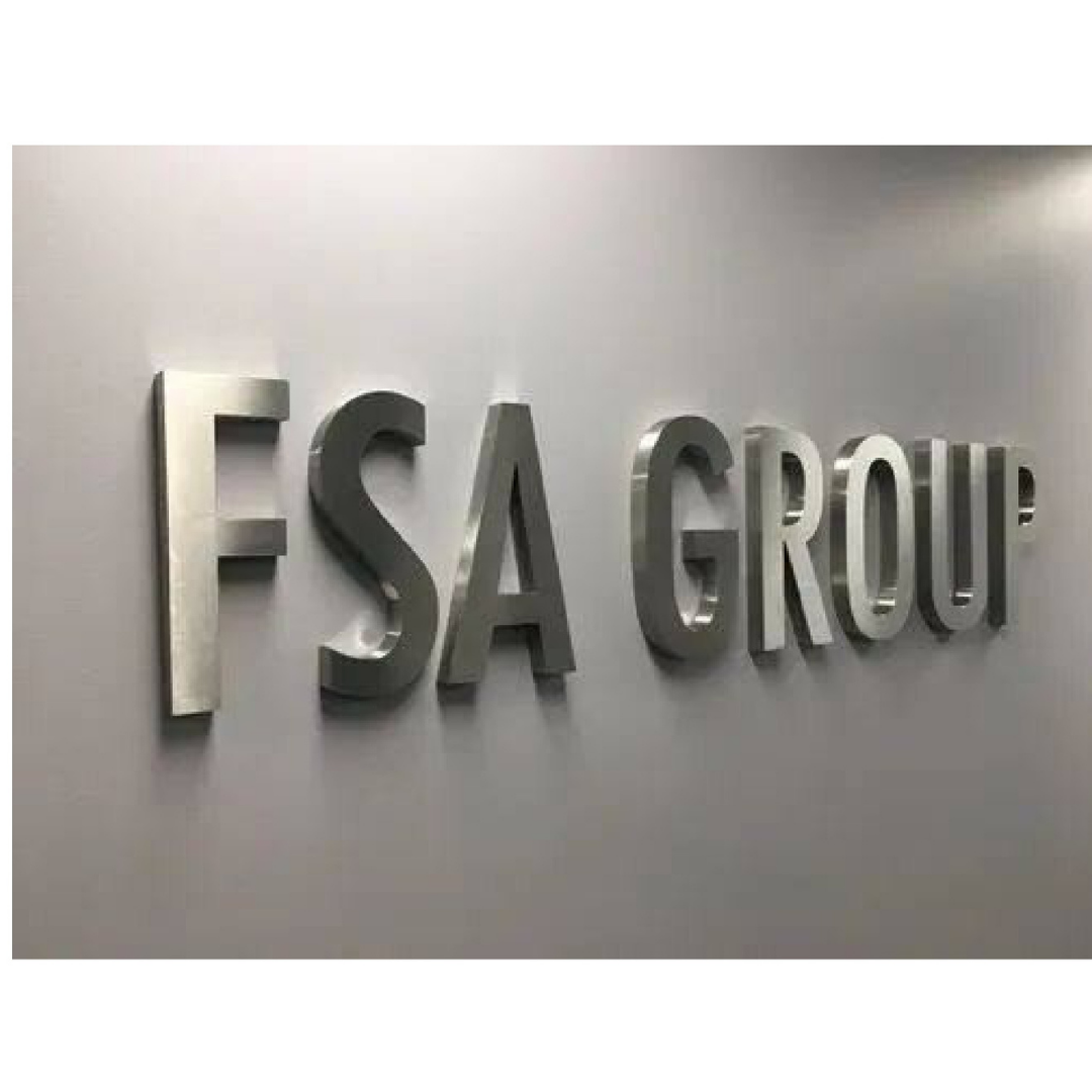 Large raised metallic letters spelling “FSA GROUP” mounted individually on a clean light-gray wall.