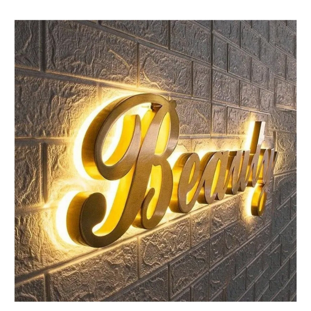 Raised metallic-gold cursive lettering spelling “Beautiful” mounted on a textured brick wall with warm LED backlighting.