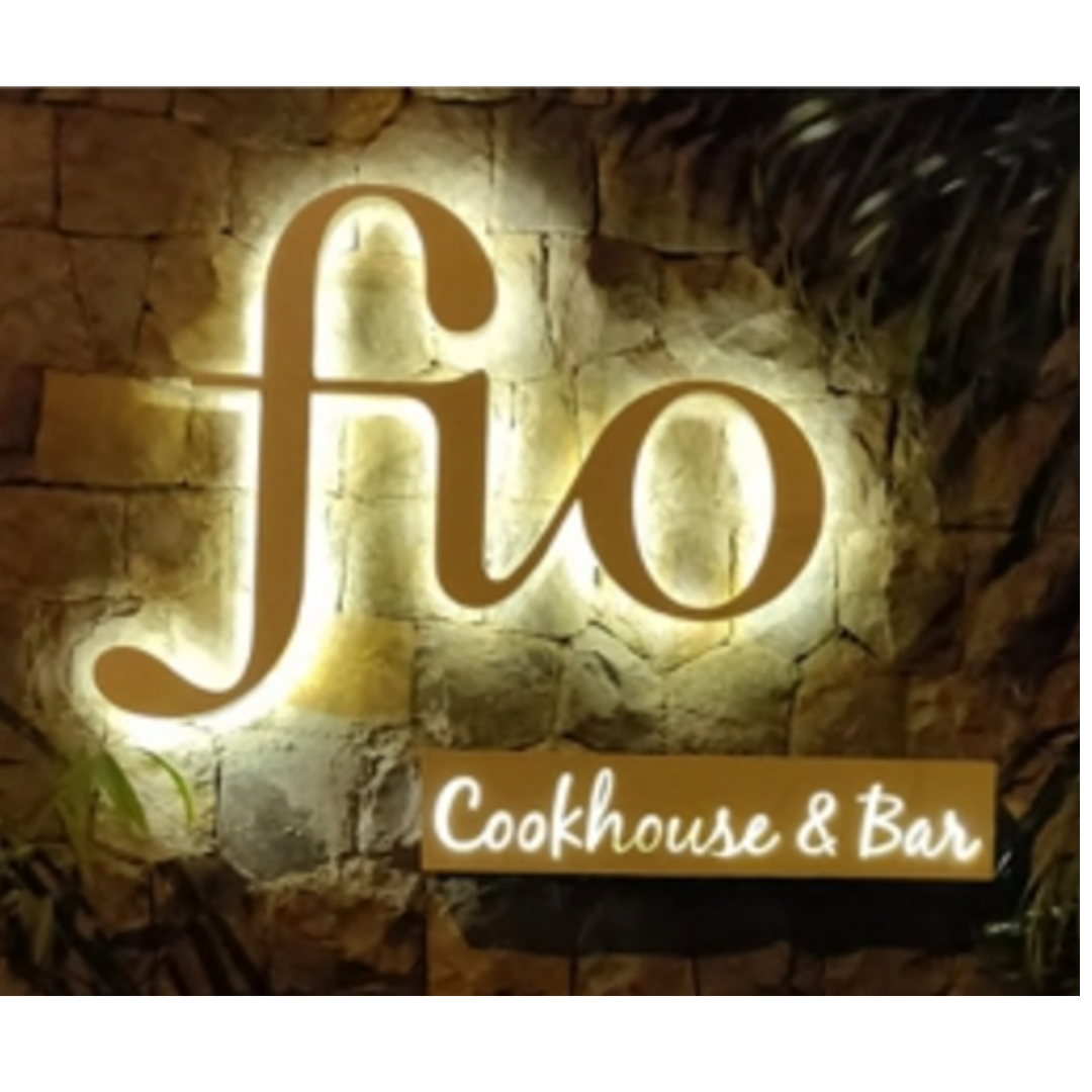 A glowing decorative sign reading “fo Cookhouse & Bar” mounted on a rustic stone wall.