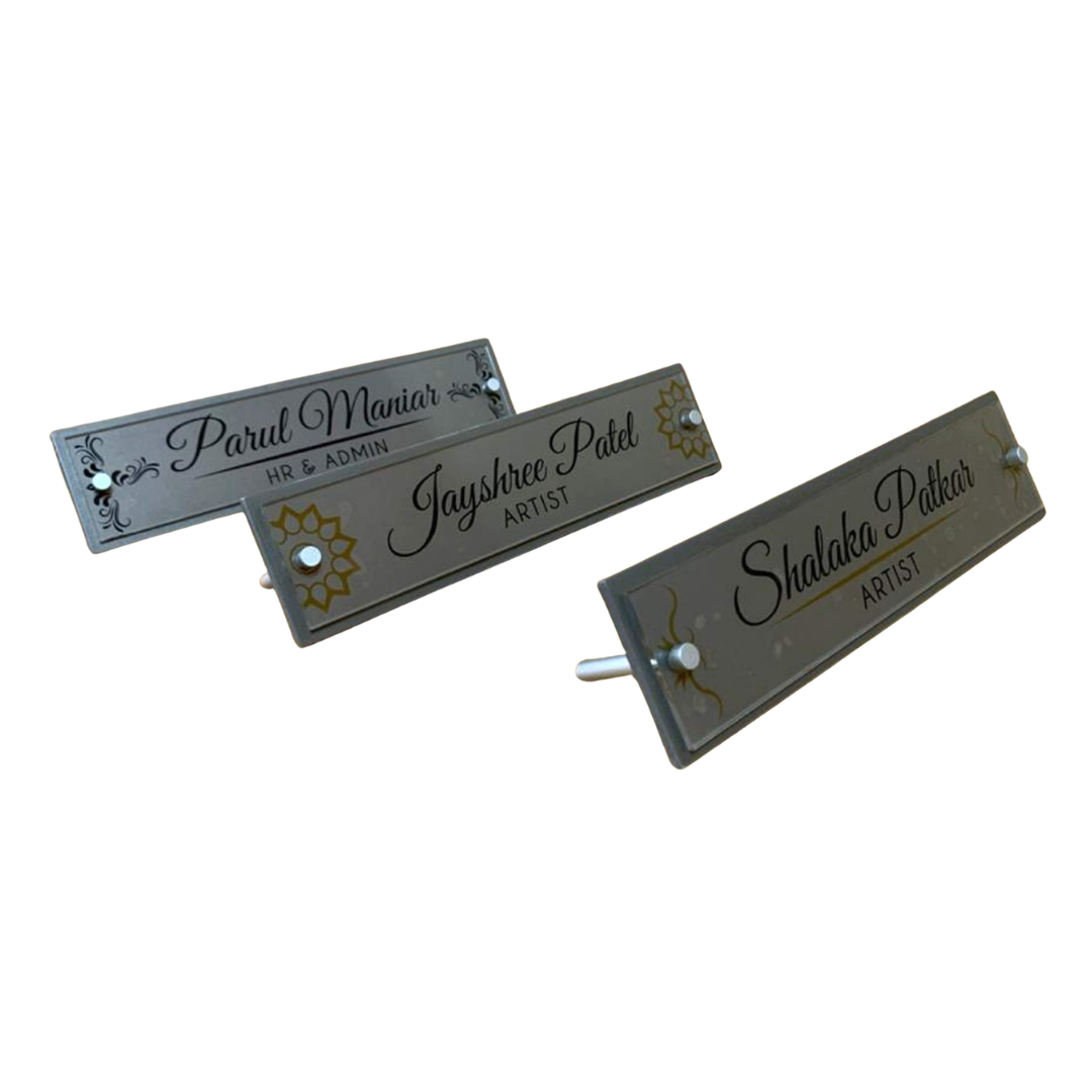 Three clear acrylic desk name plates displaying names and professional titles, including HR & Admin and Artist
