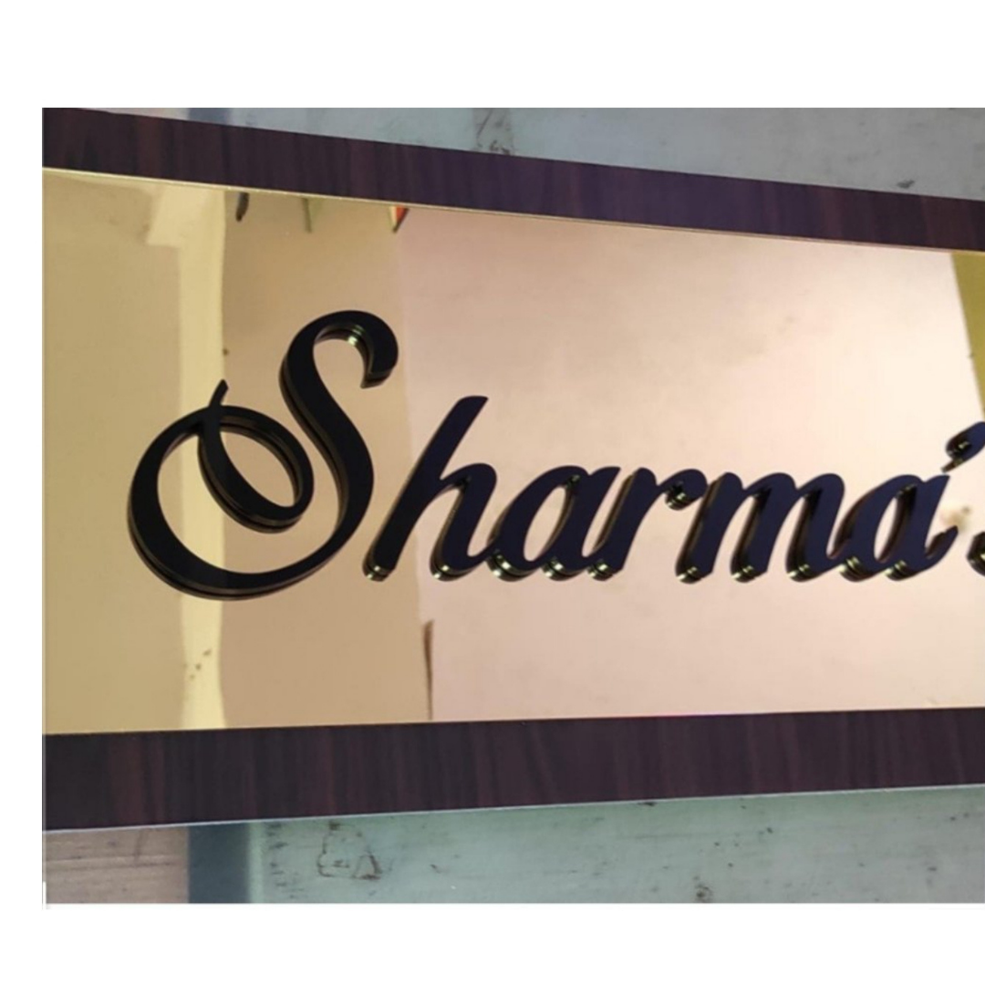 Decorative rectangular name plate with raised black cursive lettering spelling “Sharma’s” on a light-colored reflective panel with a dark wood-style border.