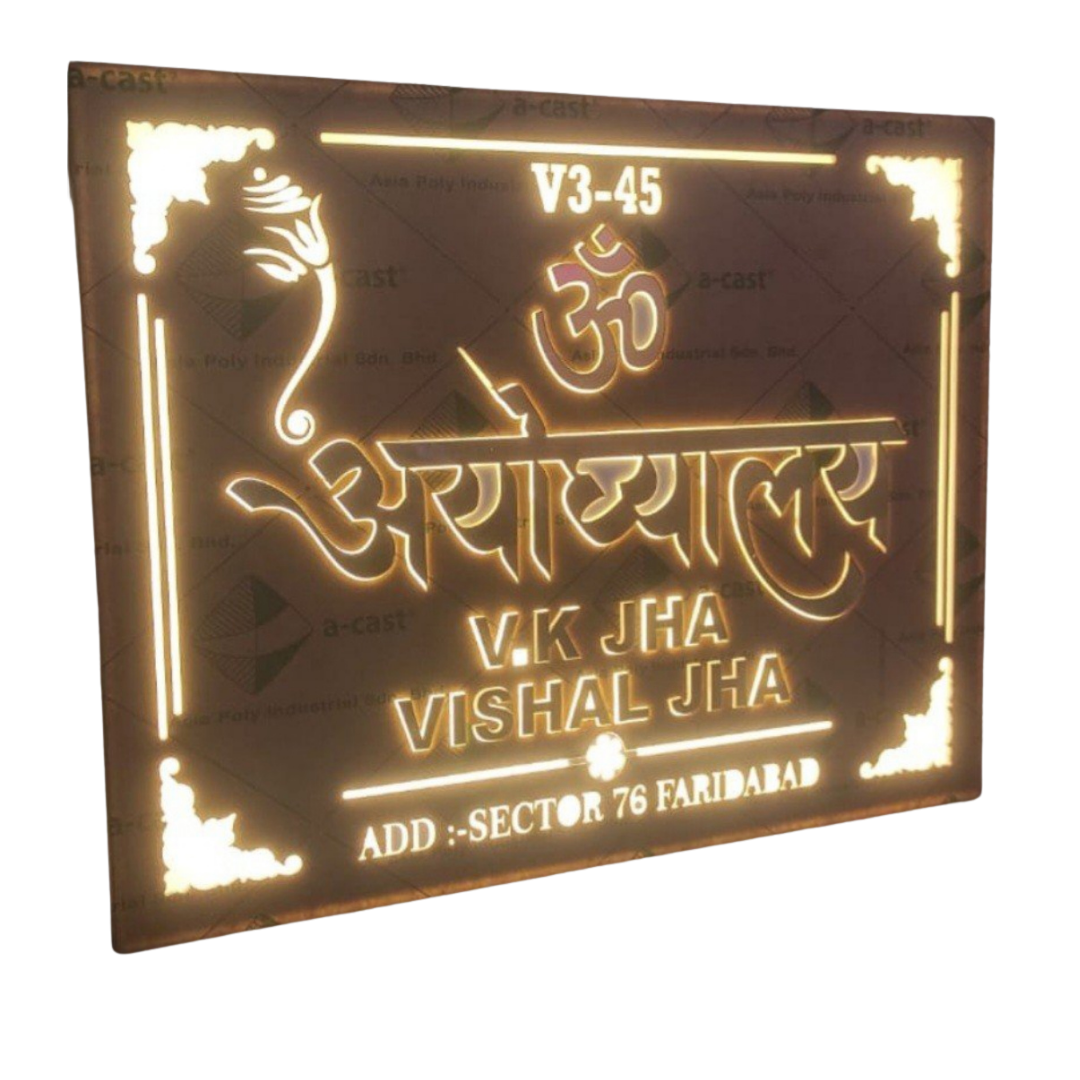 Dark rectangular wall name plate with glowing Om symbol, Hindi lettering, decorative corners, and family names