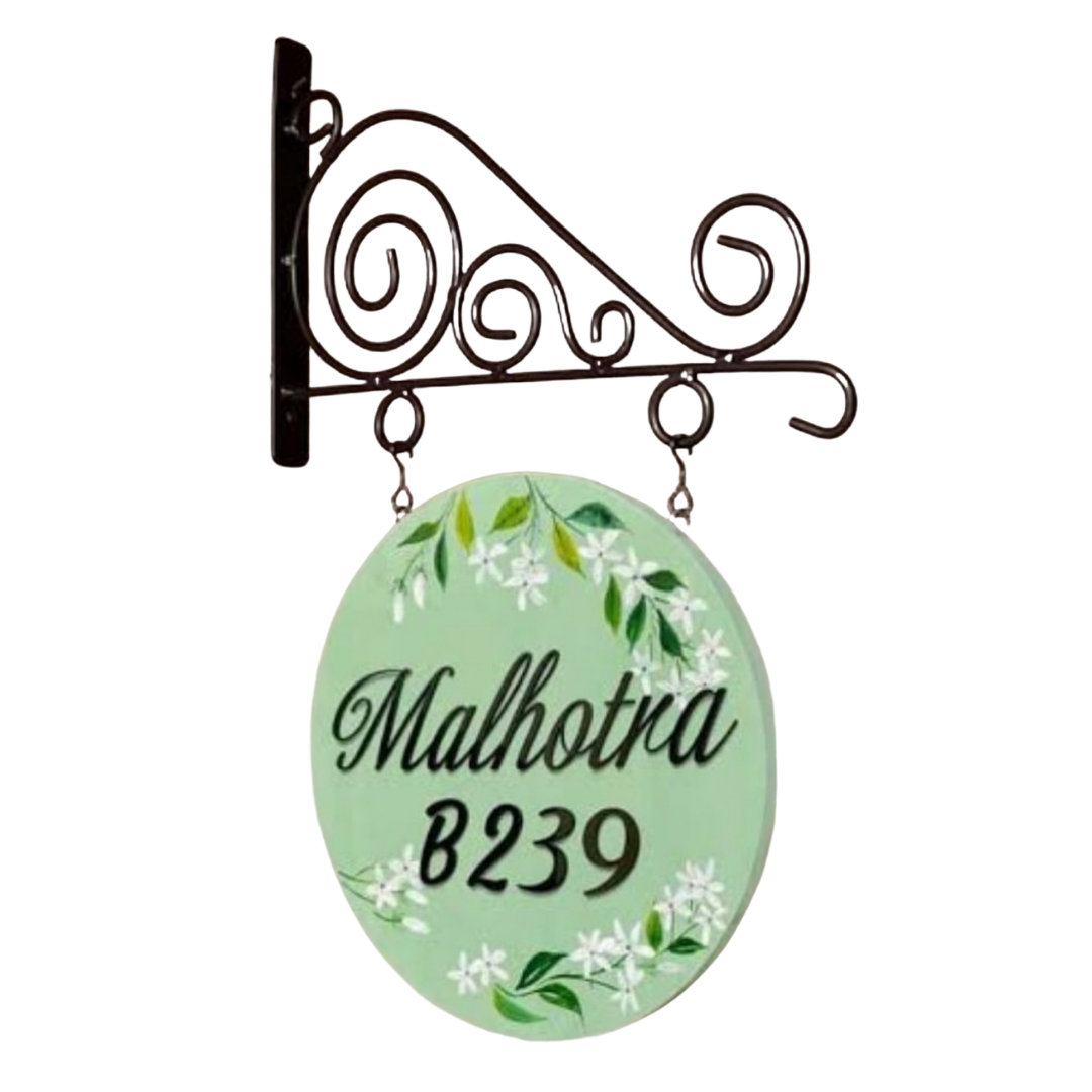 Round light-green hanging name plate reading “Malhotra” and “B239,” decorated with white flowers and green leaves.