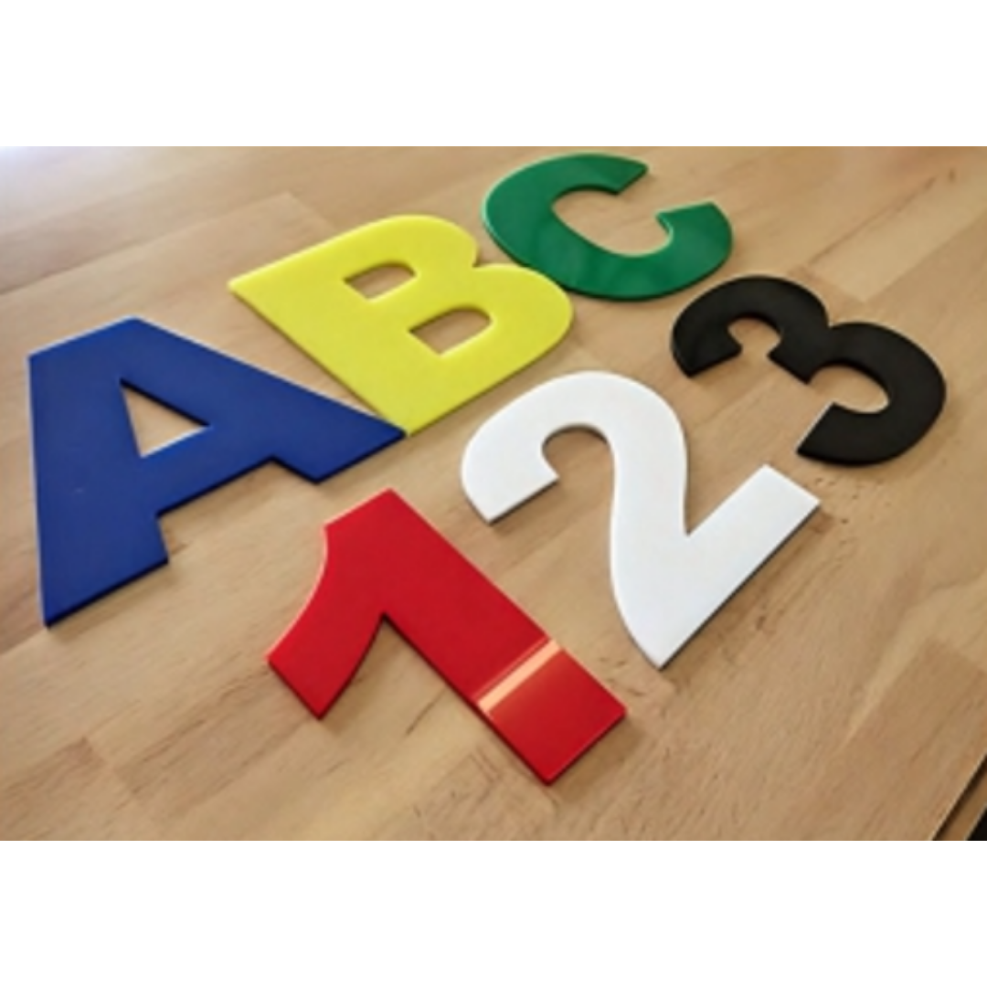 Large individual three-dimensional letters in blue, yellow, green, black, white, and red arranged on a wooden surface.