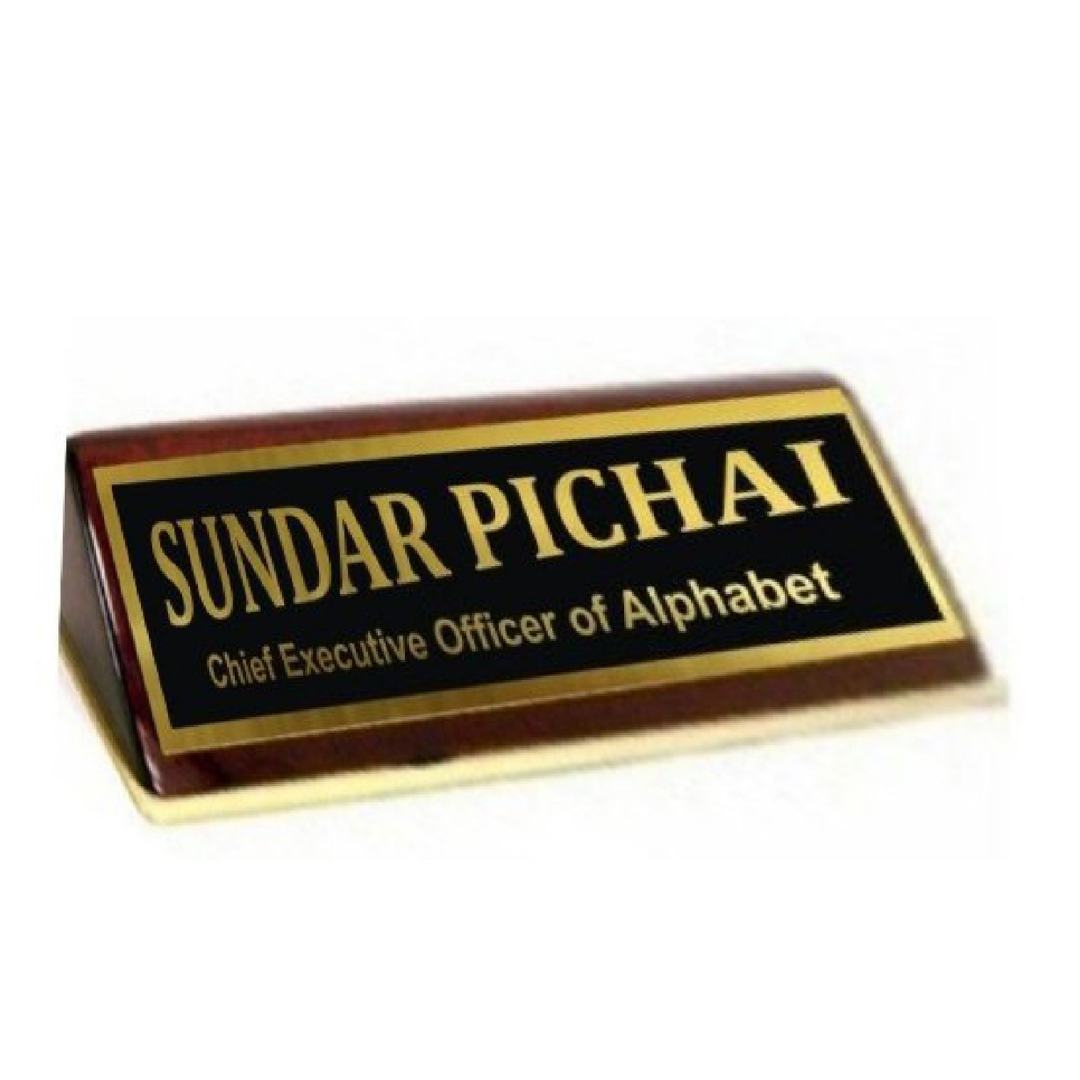 Brown wooden desk name plate with a black inset panel and gold lettering reading “SUNDAR PICHAI” and “Chief Executive Officer of Alphabet.”