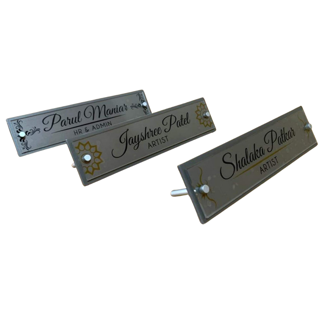 Three rectangular acrylic name plates displaying “Parul Mariah – HR & ADMIN,” “Jayshree Patel – ARTIST,” and “Shalaka Patkar – ARTIST.”