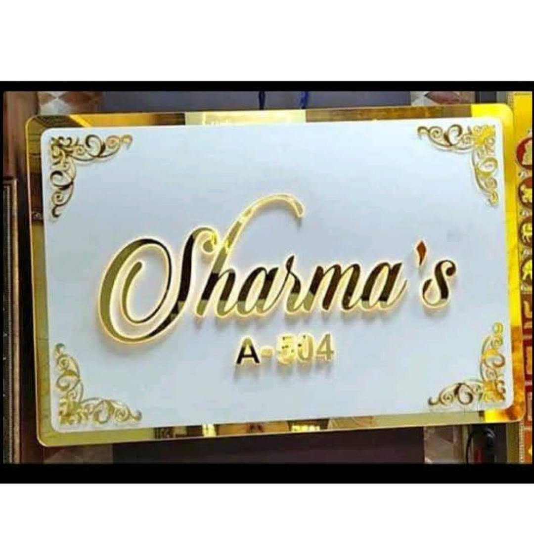 White rectangular name plate with ornate gold corners and raised cursive lettering reading “Sharma’s,” with “A-304” underneath.