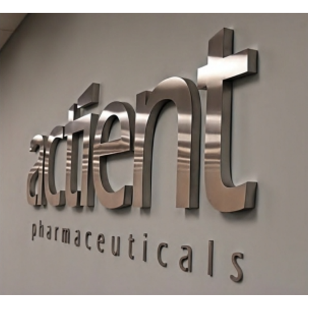Large metallic three-dimensional lettering spelling “pharmaceuticals” mounted on a light-colored wall.
