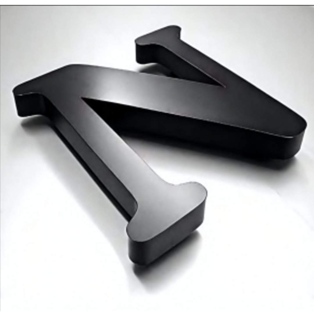 Two thick black three-dimensional cut-out letters lying on a white surface.