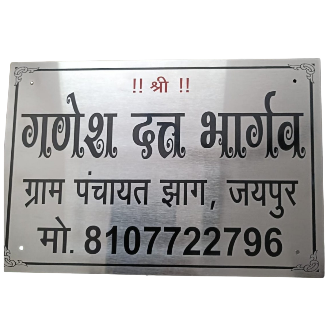 Silver rectangular metal name plate with black Hindi lettering reading “गणेश देव भाण्डा,” followed by “ग्राम पंचायत झाड़, जयपुर” and a mobile number.