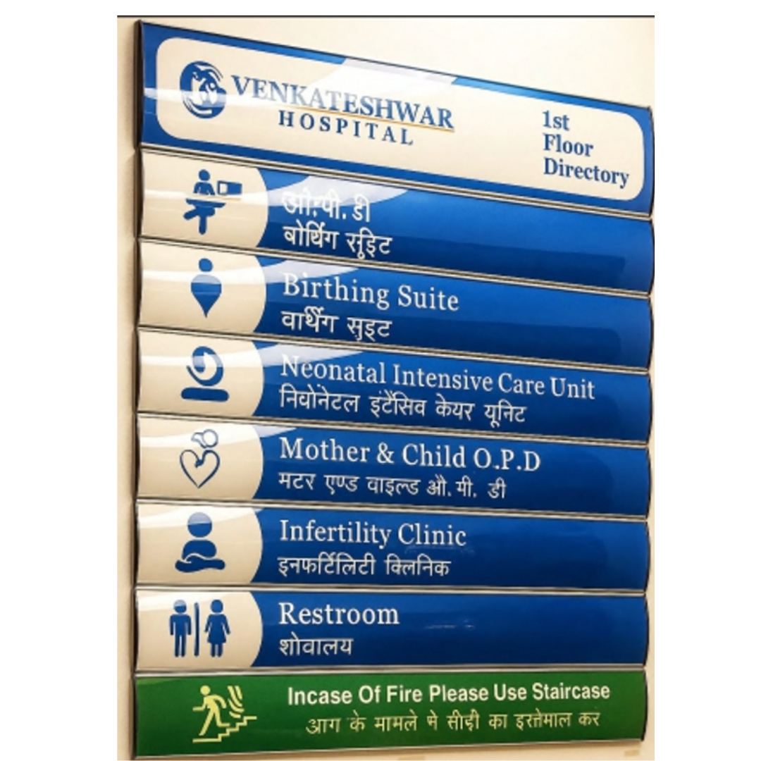 Blue-and-white bilingual hospital directory sign listing Birthing Suite, Neonatal Intensive Care Unit, Mother & Child O.P.D., Infertility Clinic, and Restroom.