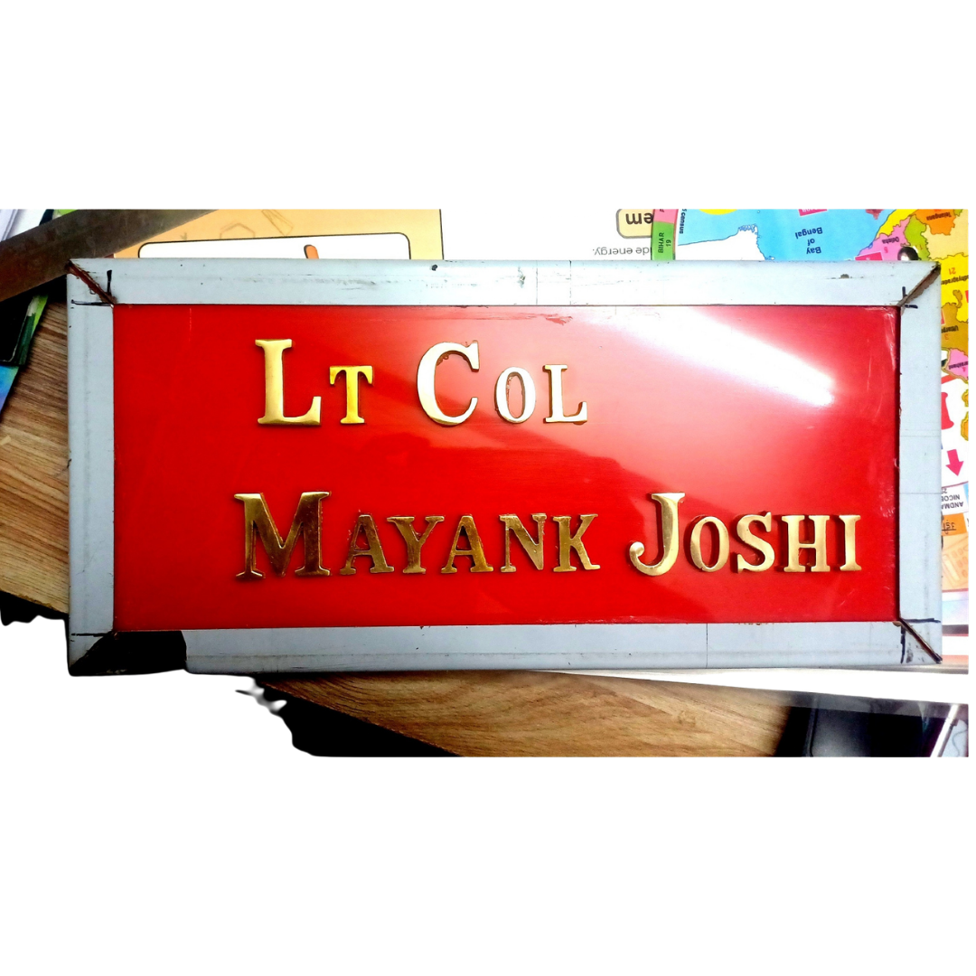 Red military name plate displaying Lt Col Mayank Joshi in raised gold lettering with a metallic border